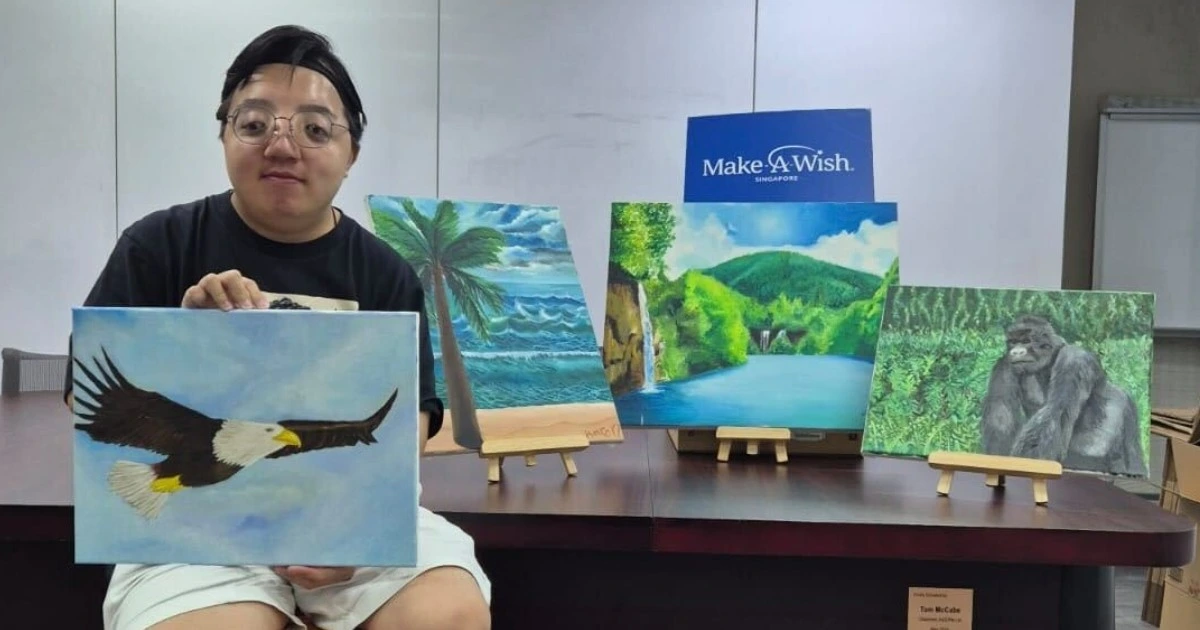 Aaron Tan posing with his artworks for the Make-A-Wish Singapore charity auction
