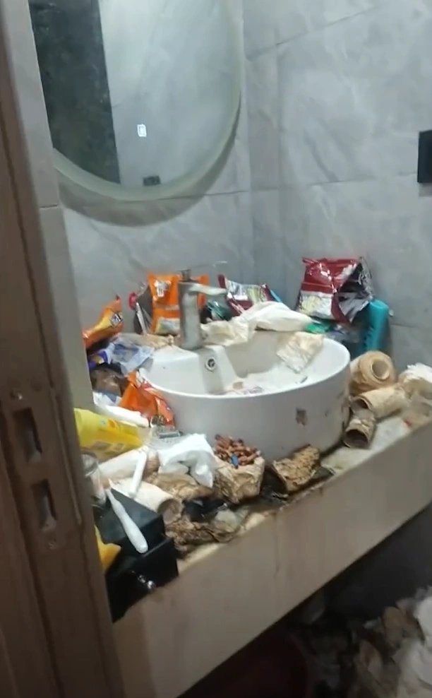 Mountains of garbage piled high next to a hotel bed.