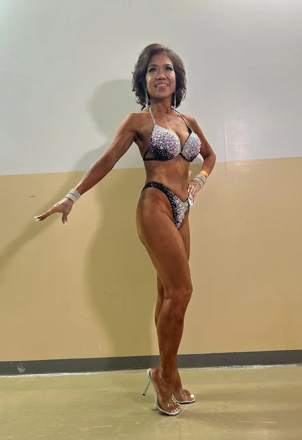 Senior woman in Taiwan performing bicep curls with dumbbells at the gym.