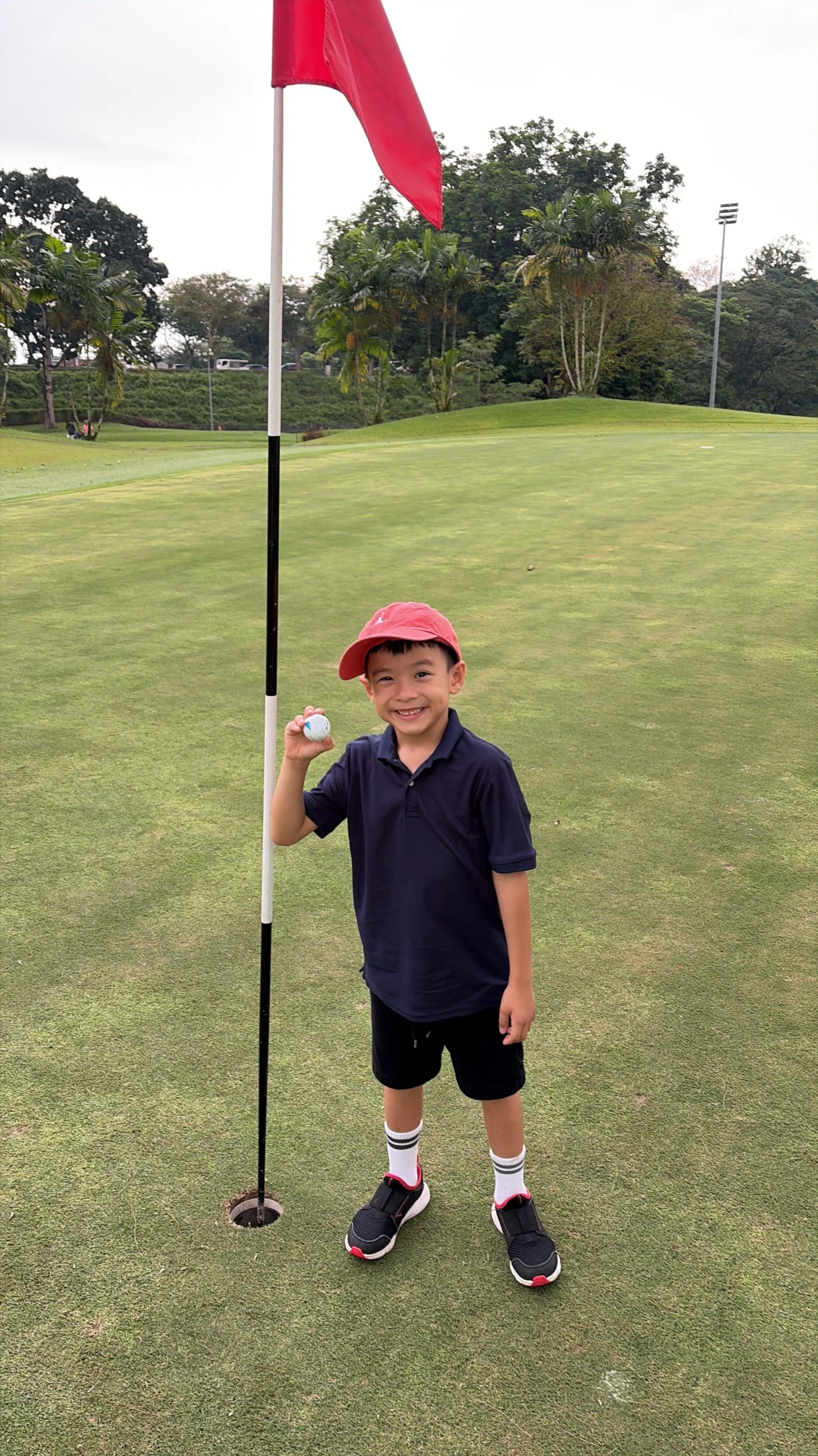Young Singaporean boy Henry performing a perfect golf swing at Mandai Executive Golf Course.