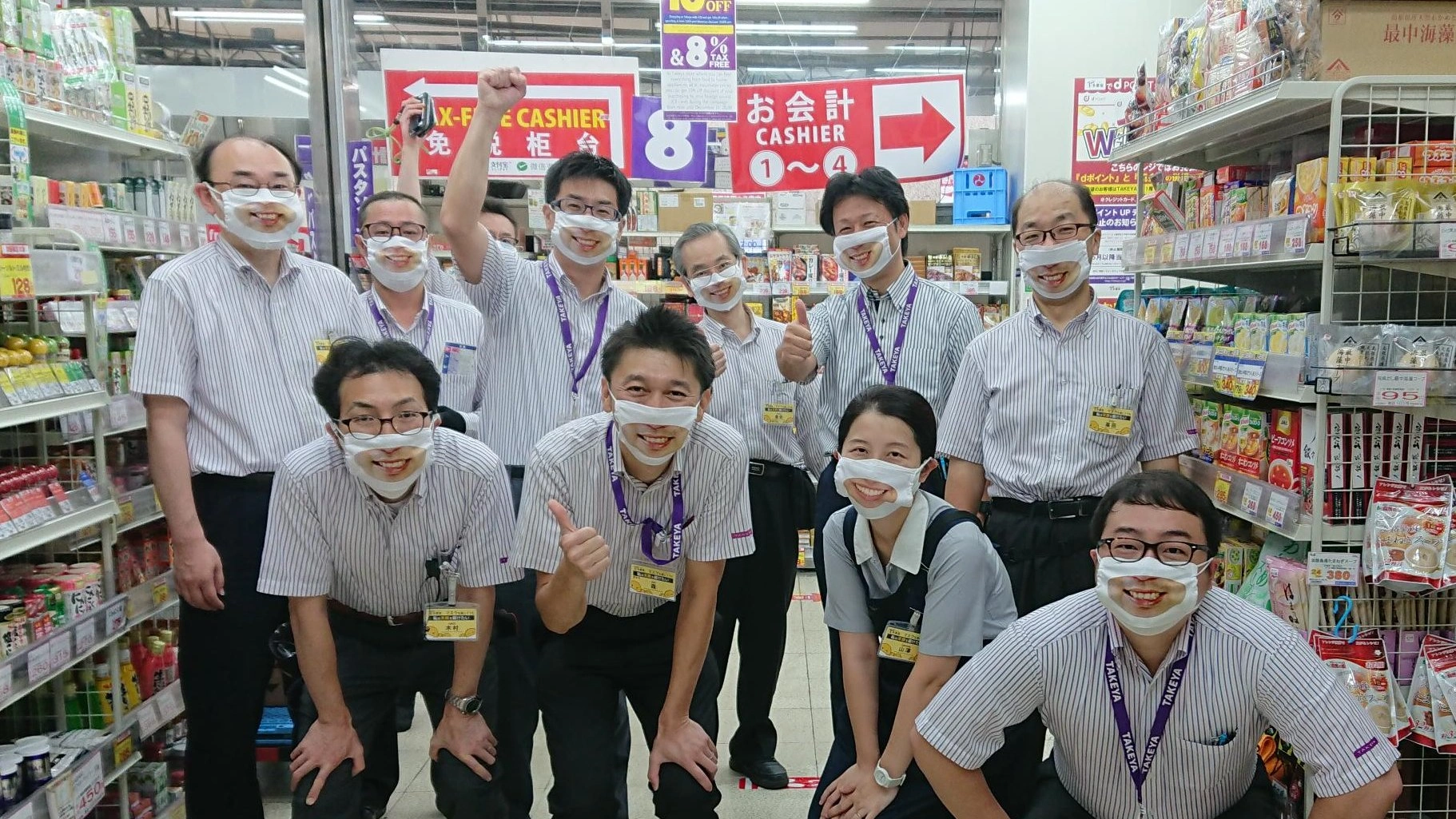 Japanese discount store clerk wearing a realistic smiling face mask at Takeya in Tokyo.