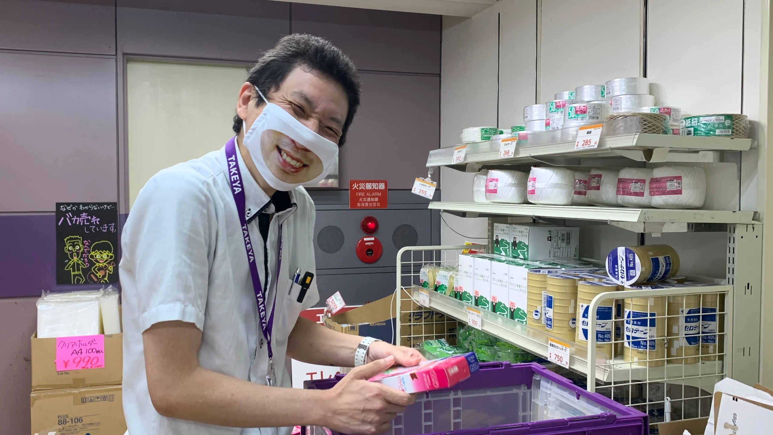 Wide angle view of staff members wearing "smile campaign" masks inside a busy Japanese retail store.