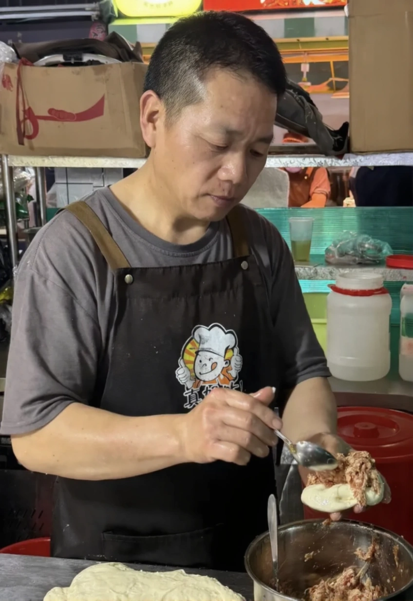  A close-up shot of a hand placing a cash donation into a transparent donation jar at a food stall.